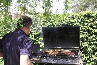 Man standing on barbecue grill in yard