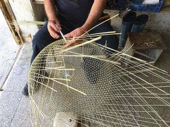 Low section of man making wicker basket