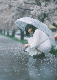 Woman holding umbrella in rainy season