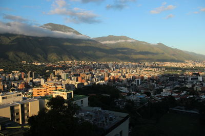 Aerial view of townscape by mountains against sky