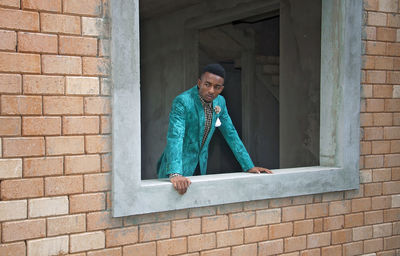 Man looking away while peeking through window