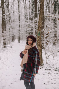 Portrait of woman standing on snow covered field