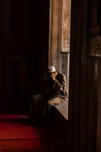 Woman sitting by door of building