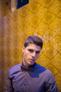 Portrait of young man standing against tiled wall