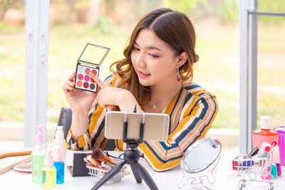 Portrait of young woman using phone while sitting on table