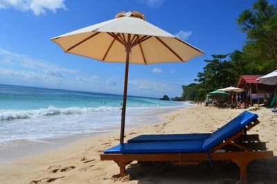 Deck chairs and parasols on beach against sky