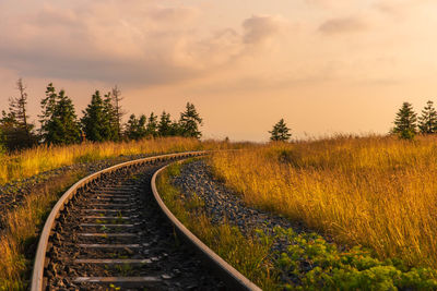 Railroad tracks on land against sky during sunset