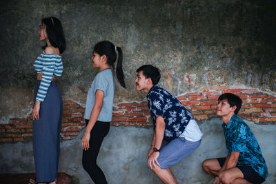 Side view of friends showing human evolution against wall