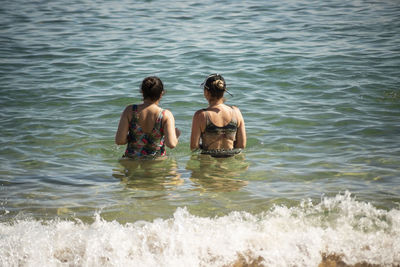 Mother and daughter in bikini entering the water at porto da barra beach in salvador, bahia.