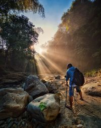 Rear view of man photographing on rocks against sky