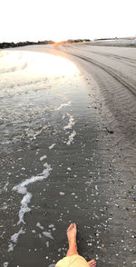 Low section of person on beach against sky