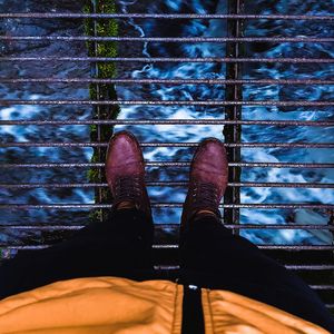 Low section of man standing on metal over river