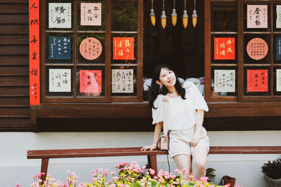 Portrait of smiling young woman standing against wall