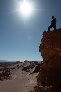 Man standing on rock on land against sky