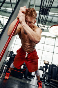 Low angle view of shirtless man exercising in gym