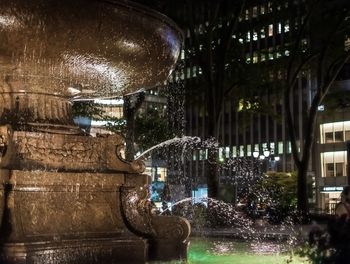 Illuminated fountain against building at night