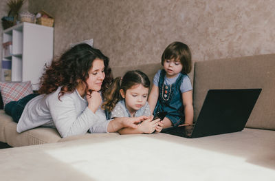 Girl and woman using phone while sitting on laptop