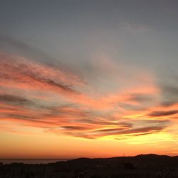 Scenic view of dramatic sky over city during sunset
