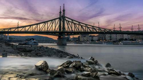 Bridge over river against sky during sunset