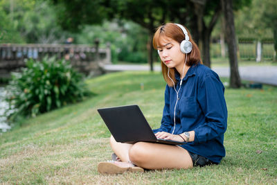 Young woman using mobile phone while sitting in park