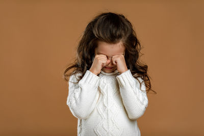 Young woman standing against yellow background