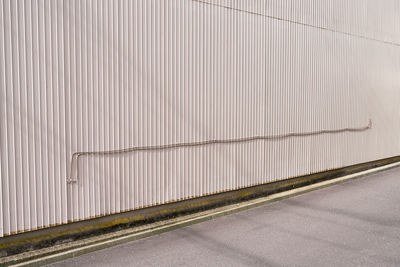 Empty road against wall with a pipe in city