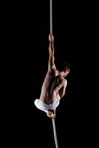 Midsection of man holding rope against black background