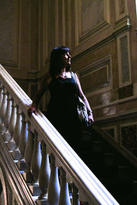 Side view of woman looking down while standing on staircase