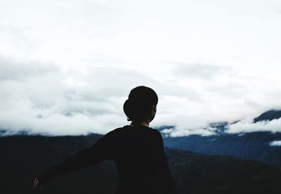 Boy standing on mountain against sky