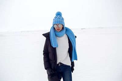 Girl running in a snowy field in a jacket and sunglasses