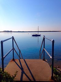 Jetty leading towards lake against clear sky