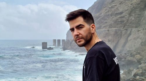 Portrait of young man looking at sea against sky