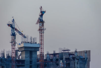 Cranes at commercial dock against sky