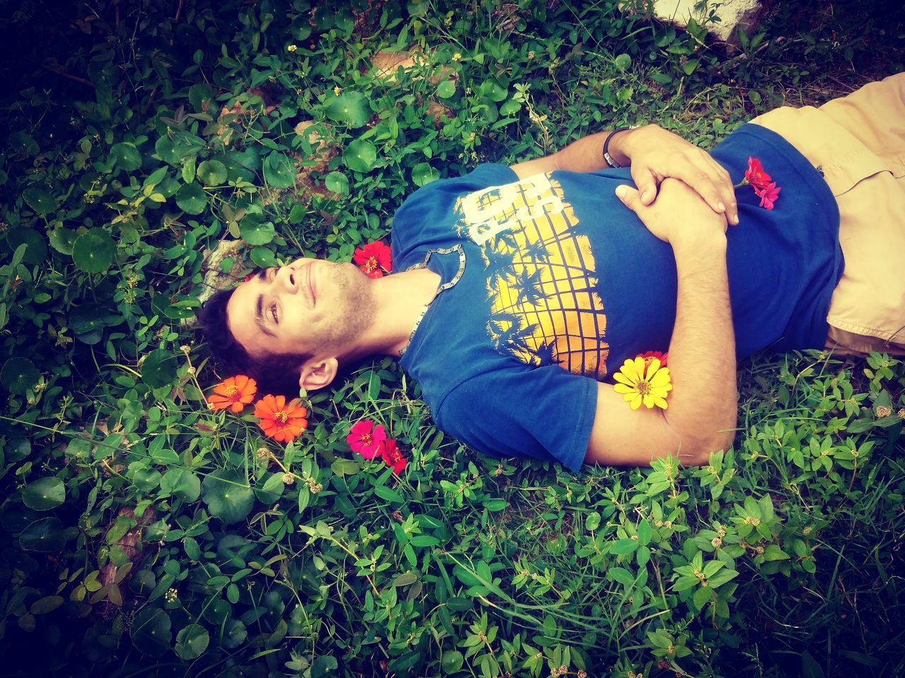 plant, lying down, nature, grass, one person, flower, high angle view, relaxation, field, land, leisure activity, lifestyles, day, growth, lying on back, green, flowering plant, outdoors, casual clothing, adult, blue, sunlight, sleeping, person, child, women, full length, young adult, autumn, clothing, smiling, yellow, red, emotion, men, leaf, resting, eyes closed, beauty in nature