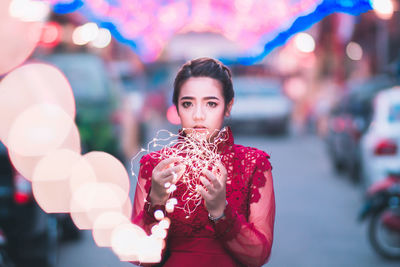Close-up portrait of young woman holding red umbrella