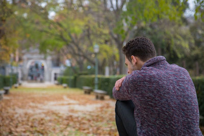 Rear view of man sitting in garden at park