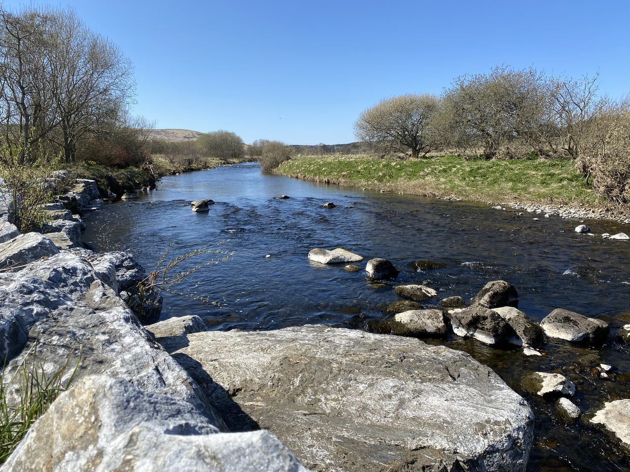 RIVER FLOWING THROUGH ROCKS AGAINST CLEAR SKY