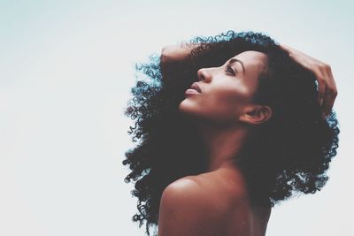 Side view of young woman looking away against sky