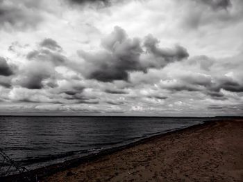 Scenic view of beach against cloudy sky