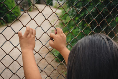 Low angle view of men by chainlink fence