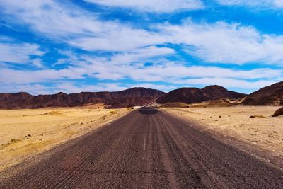 Scenic view of road amidst desert against sky