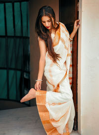 Young woman wearing sari standing by wall