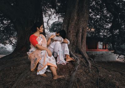 Friends sitting on tree trunk