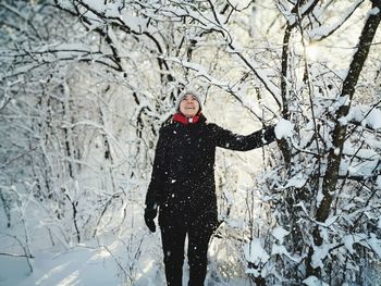 Young woman standing by bare trees during winter