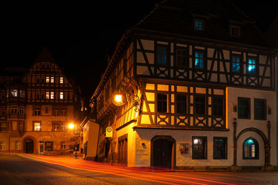 Illuminated street amidst buildings at night