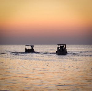 Boat sailing in sea at sunset