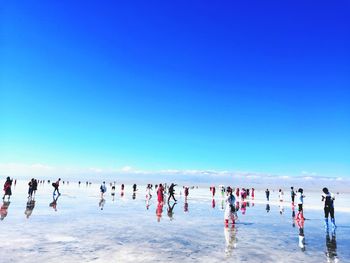 Group of people in water against clear blue sky