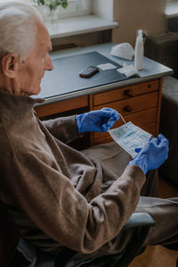 Senior man holding surgical mask at home