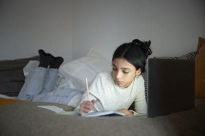 Girl doing homework with laptop in her bedroom