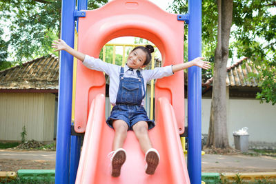 Portrait of girl with arms outstretched playing on slide